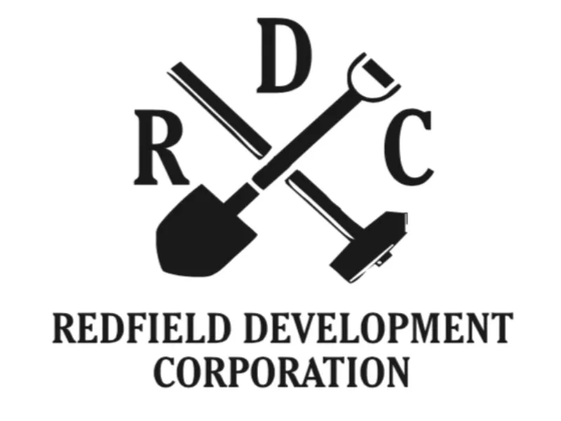 Redfield Development Corporation logo with crossed shovel and broom