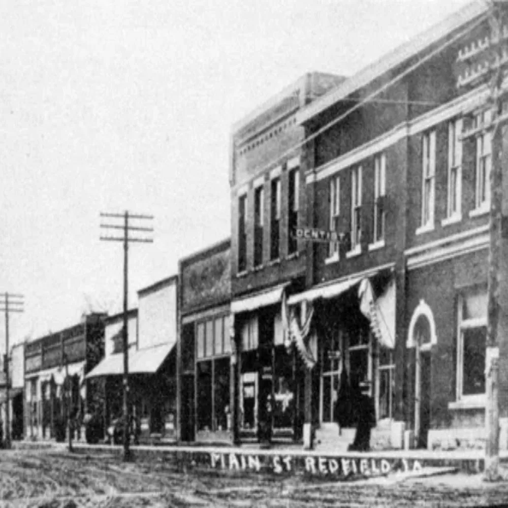 Historic black-and-white photograph of storefronts along Main Street in Redfield, Iowa