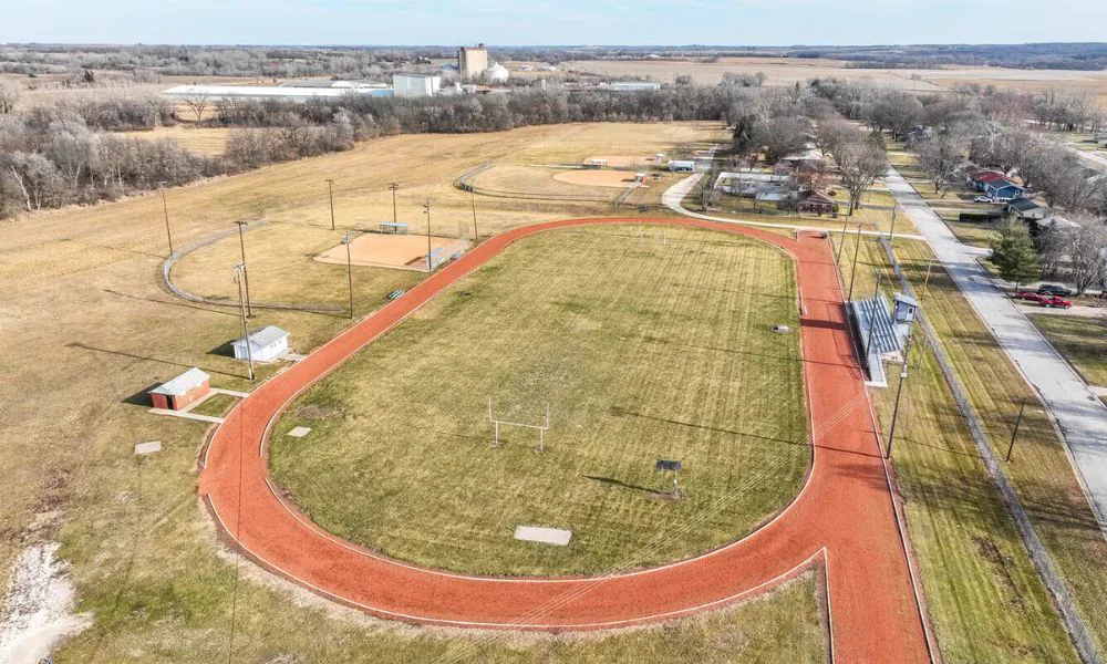 Aerial view of the WCV Redfield Recreation Complex in Redfield — a red running track circling a grass football field, with a baseball diamond, ballfields, and bleachers nearby.