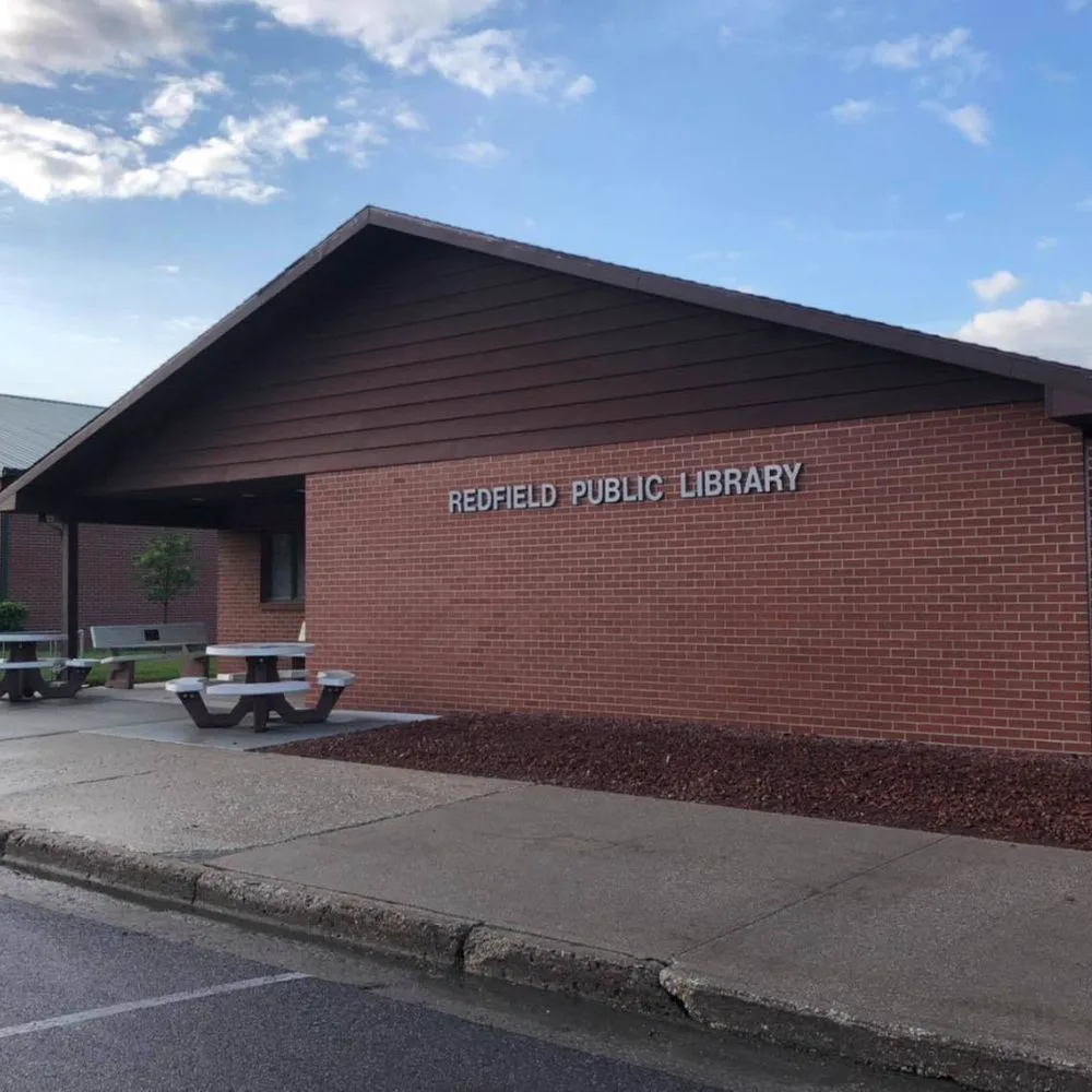 Redfield Public Library's brick exterior and entrance on Thomas Street under a blue sky.