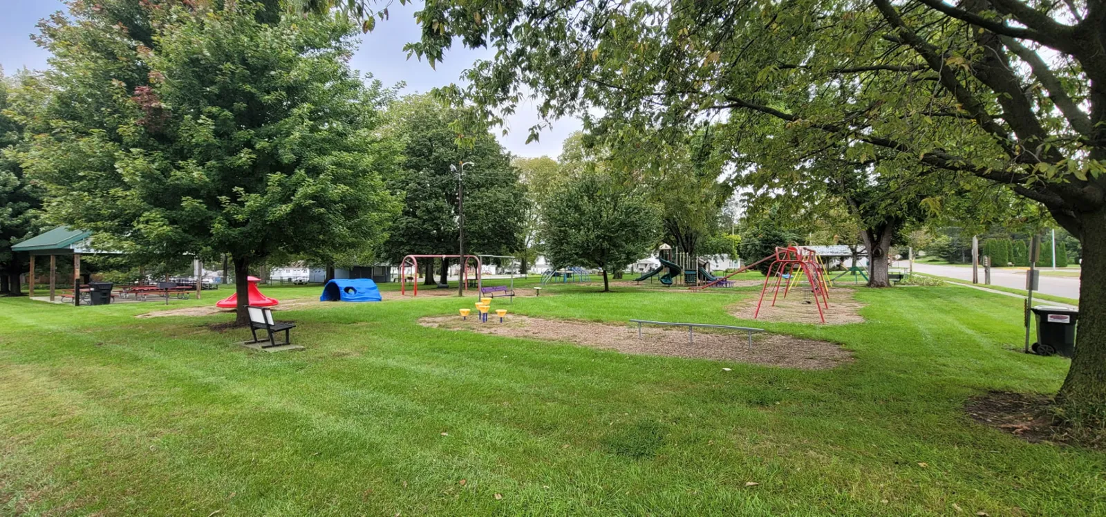 The outdoor basketball court at Redfield City Park, bordered by a wide mowed lawn and shade trees