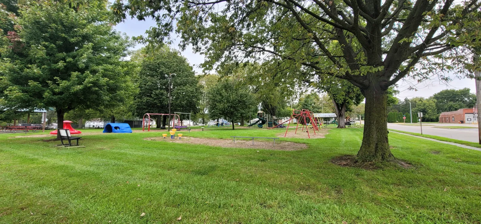 The Redfield City Park shelter with red picnic tables, maintained by the Redfield Lions Club, beside the playground lawn