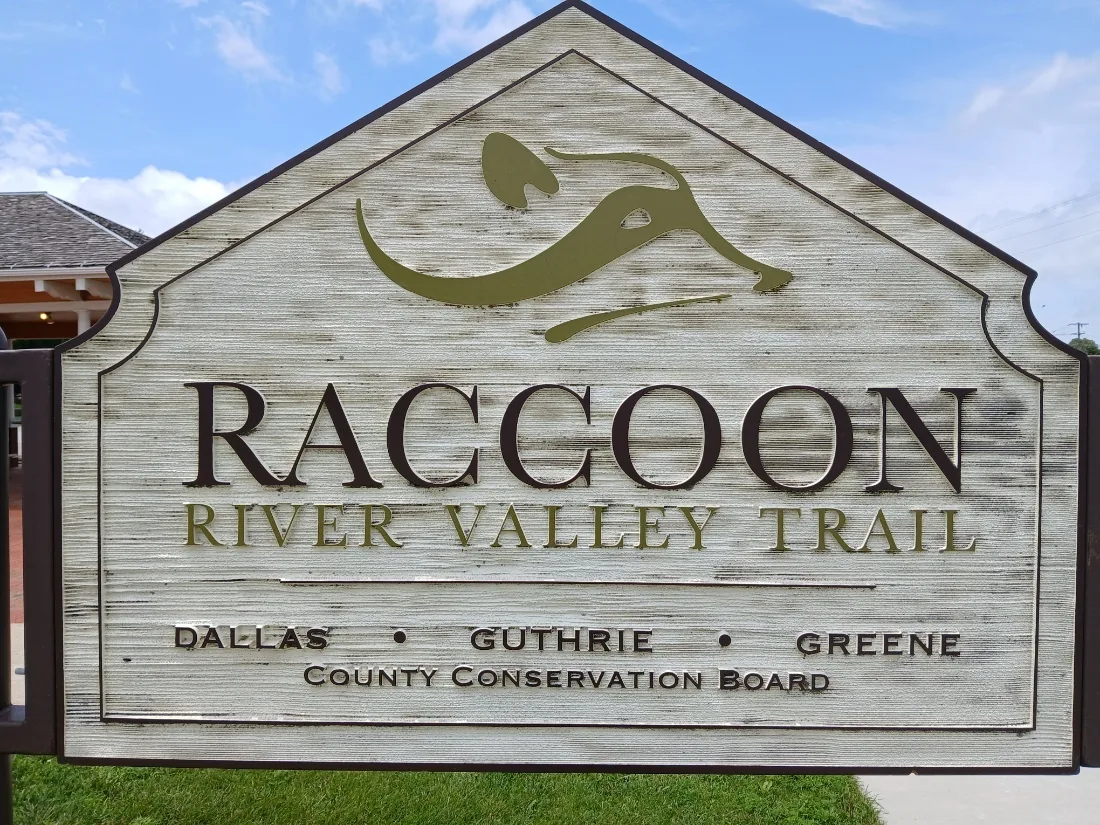 Raccoon River Valley Trail identification sign at the Redfield depot trailhead, listing the Dallas, Guthrie, and Greene County Conservation Board