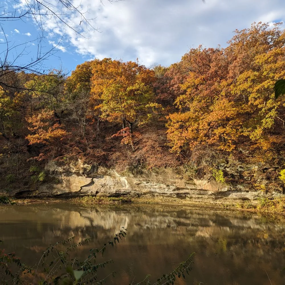 Sandstone ledge and autumn trees reflected in the Middle Raccoon River