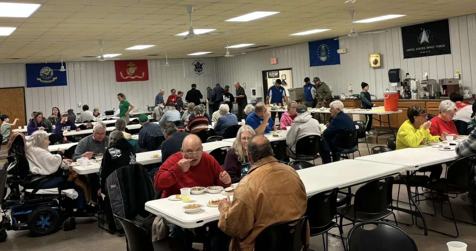 Community members sharing a meal at long tables inside the Legion Hall during the Winterfest chili feed