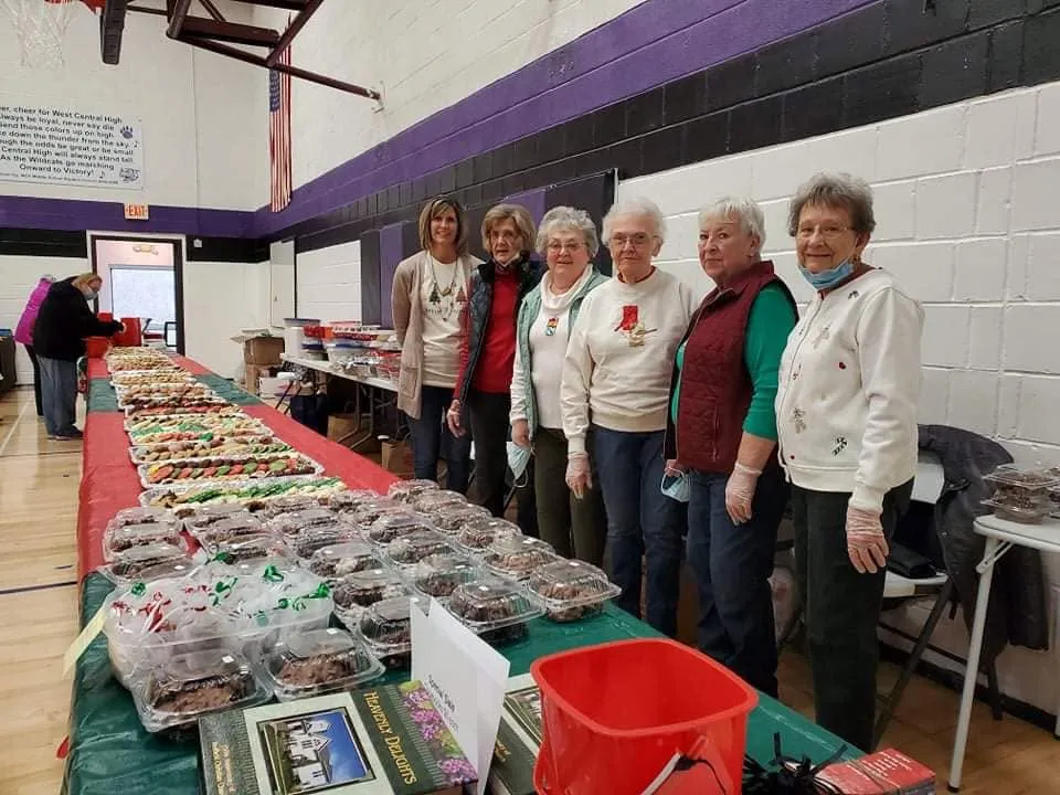 Volunteers standing behind tables filled with holiday cookies at the Winterfest Cookie Walk