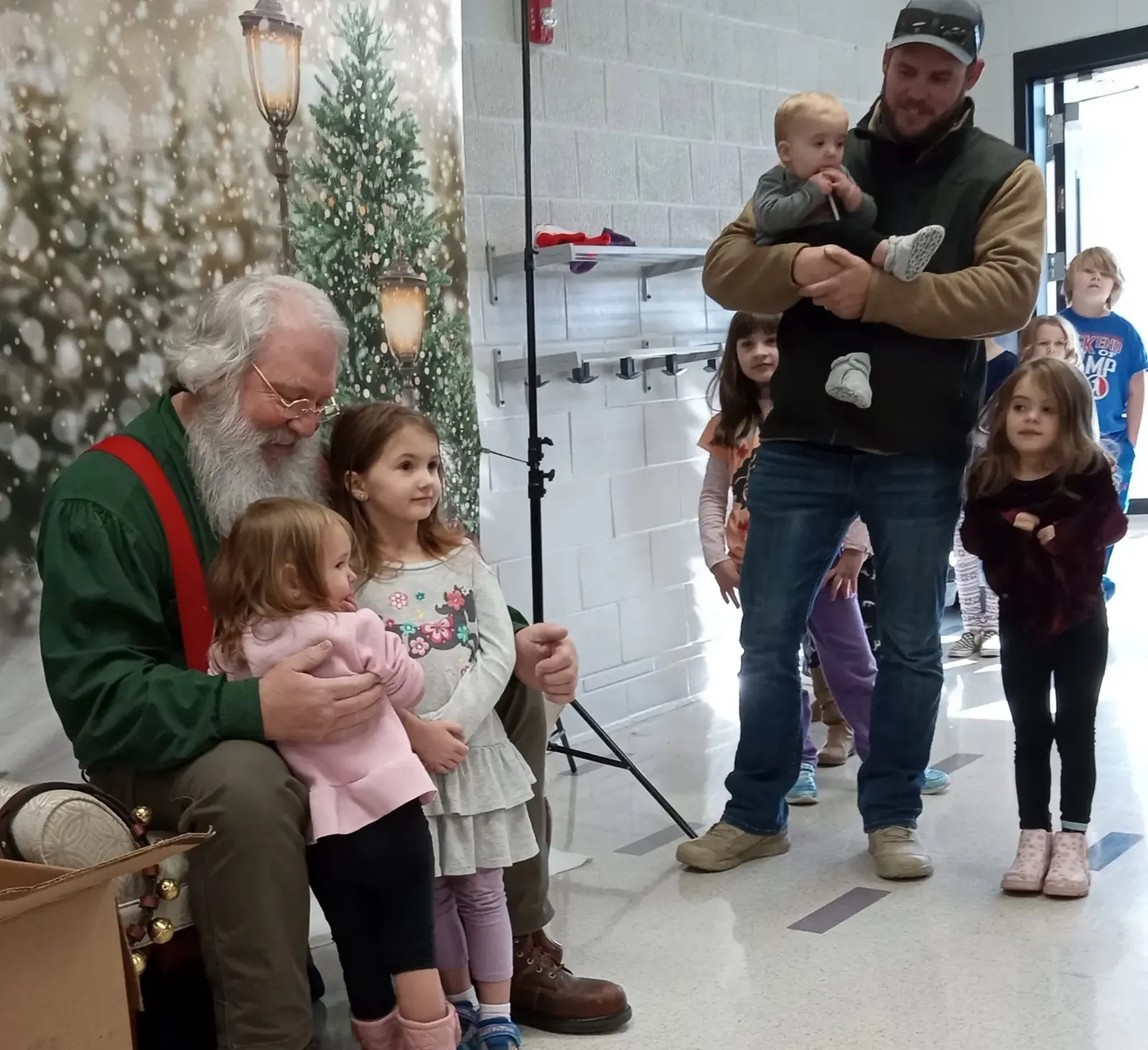 Young children visiting Santa in front of a snowy holiday backdrop at Winterfest